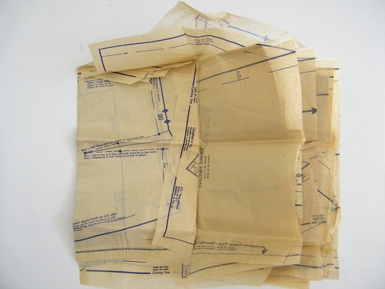May include: A vintage sewing pattern with instructions and diagrams printed on beige paper. The pattern includes a cutting line and a fold line.