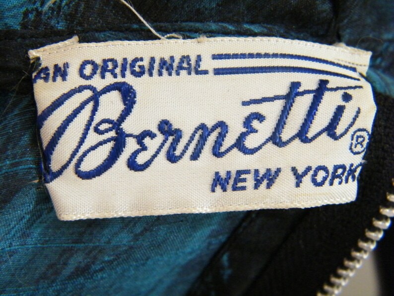 May include: A white label with blue embroidered text that reads "An Original Bernetti New York" with a registered trademark symbol.