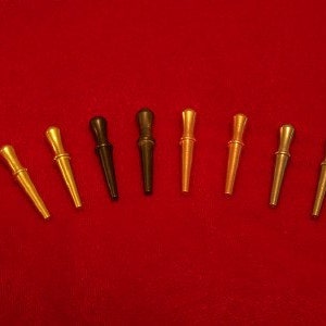 May include: A set of eight metal knitting needles in various colors, including gold, silver, and black. The needles are arranged in a semi-circle on a red surface.