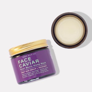 Może przedstawiać: Słoik Face Caviar Snail Mucin Sleep Mask ze złotą pokrywką i fioletową etykietą. Etykieta zawiera tekst "GONE WILD CO." i szczeg&oacute;ły produktu. Otwarty słoik maski znajduje się obok. Produkt ma 59 ml.