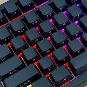 May include: A close-up shot of a black mechanical keyboard with illuminated keys. The keys are black with white lettering. The keyboard features function keys such as Ctrl, Shift, Tab, Caps, and Win. The keys are lit with red, orange, and purple lights.