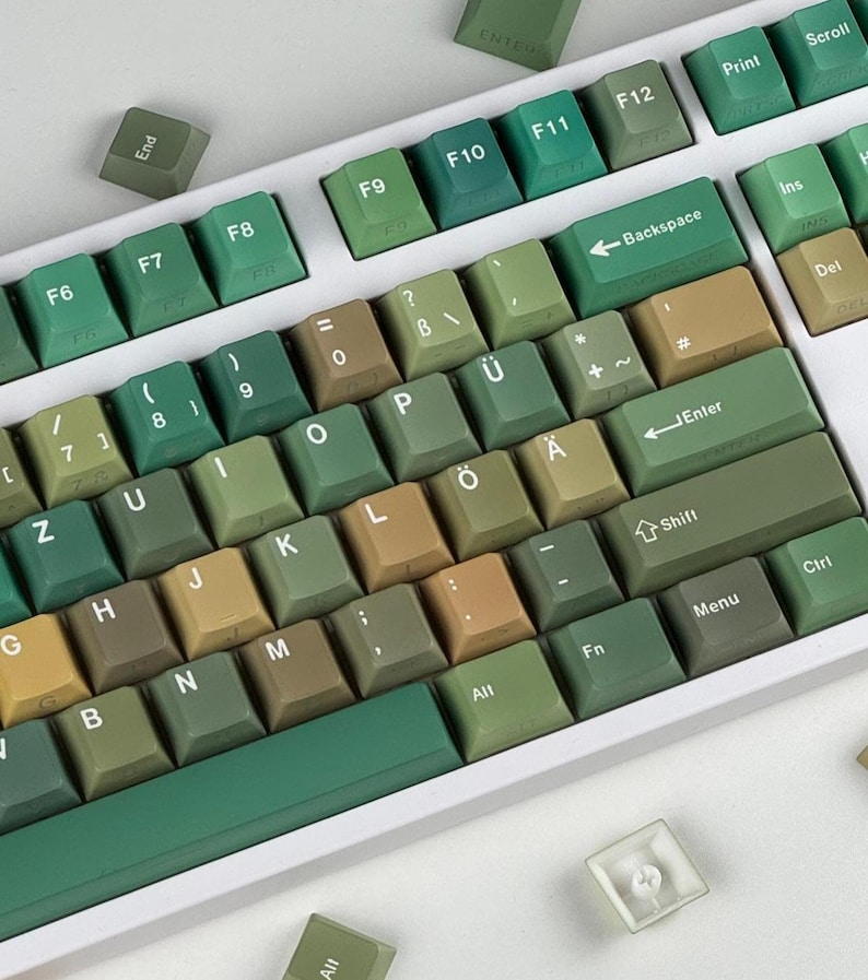 May include: A mechanical keyboard with green and tan keycaps. The keycaps are arranged on a white base, with various function keys and letters visible. The keyboard has a minimalist design, with a focus on the keycaps' color scheme.