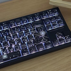 May include: Black mechanical keyboard with white keycaps featuring a circuit board design. The keys are backlit with a bright white light. The keyboard has function keys, arrow keys, and a number pad.