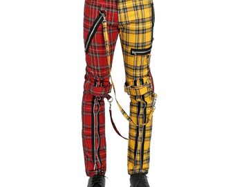 May include: Red and yellow plaid pants with multiple zippers and straps. The pants are split down the middle, with one side red and the other yellow. The pants have black zippers and straps, and are worn with black shoes.
