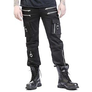 May include: Black cargo pants with multiple pockets, silver zippers, and metal hardware. The pants have a straight leg design and are paired with black combat boots. The overall style is edgy and alternative.
