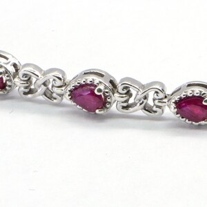May include: A silver bracelet with a delicate chain and five oval-shaped ruby gemstones.