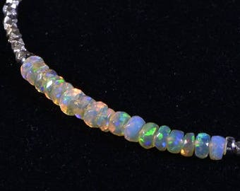 May include: A silver bracelet with a row of iridescent opal beads. The bracelet is made of small, faceted silver beads.