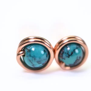 May include: A pair of copper wire wrapped earrings with turquoise stones.