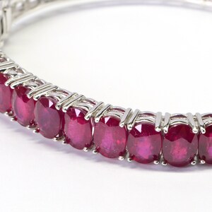 May include: A silver bracelet with a row of oval-shaped ruby gemstones.