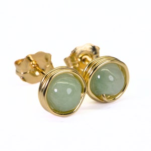 May include: A pair of gold wire wrapped earrings with light green gemstone cabochons.