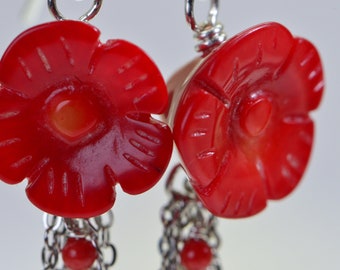 May include: A pair of red coral flower earrings with silver chains and beads. The flowers are carved with intricate details and have a glossy finish.