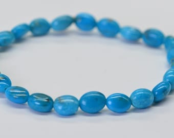 May include: A turquoise gemstone bracelet with oval-shaped beads.