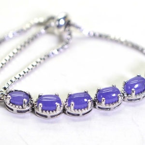 May include: A silver chain bracelet with a purple gemstone accent. The bracelet has an adjustable sliding clasp.
