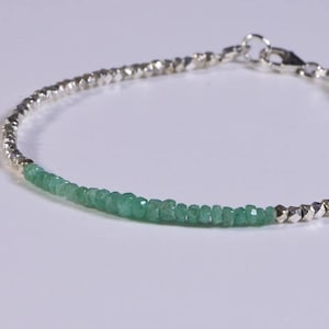 May include: A silver and green beaded bracelet with a silver clasp. The bracelet is made with small, faceted beads.