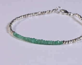 May include: A silver and green beaded bracelet with a silver clasp. The bracelet is made with small, faceted beads.
