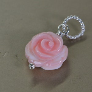 May include: A delicate pink coral rose charm pendant with a silver twisted rope bail.
