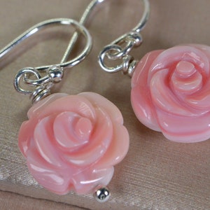 May include: A pair of silver earrings with pink rose-shaped coral pendants.
