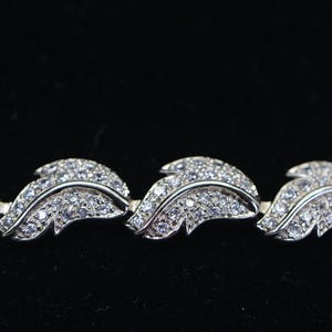 May include: A silver bracelet with a leaf design, featuring small clear stones.