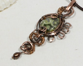 May include: A copper wire wrapped pendant with a green and white stone and a brown pearl at the bottom.