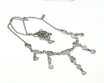 Pode incluir: Um colar de corrente de prata com um pingente feito de vários diamantes brutos. Os diamantes são engastados em prata e penduram da corrente em um design em cascata.