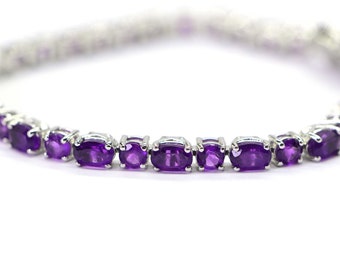 May include: A silver bracelet with a row of oval-shaped amethyst gemstones.