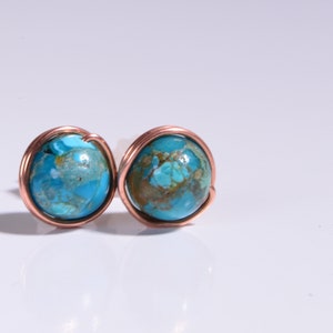 May include: A pair of copper wire wrapped earrings with blue and brown marbled stone cabochons.