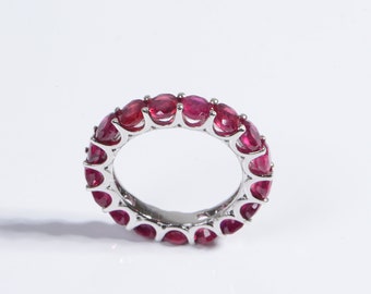 May include: A silver band ring with a row of round, red gemstones.