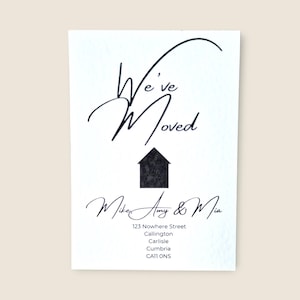 May include: A white card with the text "We've Moved" in black cursive script, above a black house graphic. The names "Mike, Amy & Mia" are written below, followed by the new address in Callington, Carlisle, Cumbria.