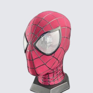 May include: A full-head fabric mask featuring a vibrant red base color with a prominent black web pattern printed across the surface. The mask includes two large, almond-shaped eye lenses with a white mesh texture and thick black frames.