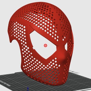 May include: A red, perforated mask with a distinctive eye shape, likely for cosplay or costume use. The mask is 3D-printed, featuring numerous small holes for breathability and a smooth, curved design. It sits on a black and gray surface.
