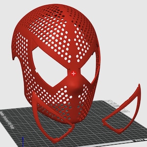 May include: A red, perforated mask with large eye openings and a nose piece, resembling a superhero mask. The mask is accompanied by two detached, curved pieces, possibly for the lower face or neck. The design suggests a 3D-printed or digitally designed item.