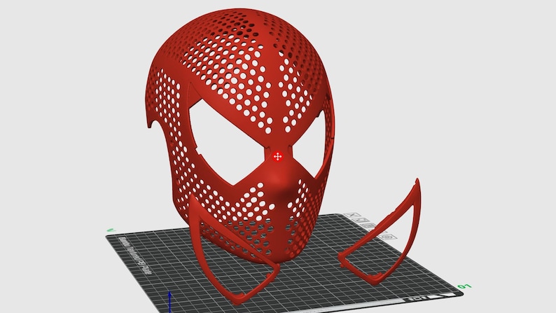 May include: A red, perforated mask with large eye openings and a nose piece, resembling a superhero mask. The mask is accompanied by two detached, curved pieces, possibly for the lower face or neck. The design suggests a 3D-printed or digitally designed item.