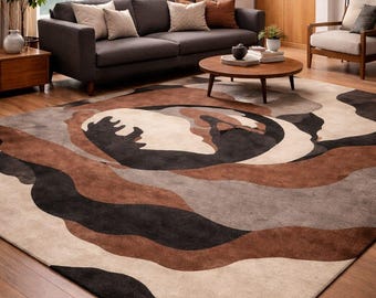 May include: A large area rug with a modern design featuring flowing, organic shapes in shades of brown, black, gray, and cream. The rug is placed on a hardwood floor in a living room setting, with a dark gray sofa and wooden furniture.