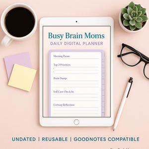 Puede incluir: Una tableta muestra un planificador digital "Busy Brain Moms Daily Digital Planner". El planificador incluye secciones para el enfoque matutino, prioridades, lluvia de ideas, autocuidado y reflexión vespertina. También hay una taza de café, notas adhesivas, una suculenta, gafas y un lápiz óptico.