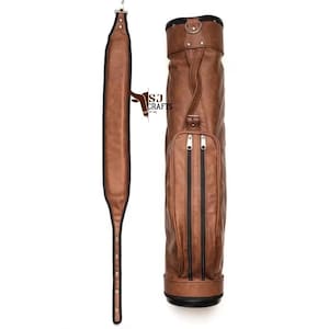 May include: A brown leather golf bag with a matching shoulder strap. The bag has two vertical zippered pockets and a handle. The shoulder strap is long and adjustable. The bag has the text "SJ Crafts" on it.