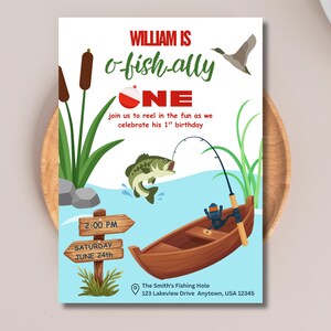 May include: A birthday invitation card featuring a fishing theme with a brown boat, a green fish, a fishing rod, cattails, and a duck. The text reads: WILLIAM IS o-fish-ally ONE join us to reel in the fun as we celebrate his 1st birthday 2:00 PM SATURDAY JUNE 24th The Smith's Fishing Hole 123 Lakeview Drive Anytown, USA 12345.