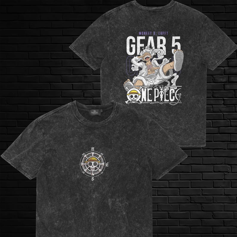 May include: A charcoal gray acid-wash t-shirt featuring a small compass and skull graphic on the front. The back displays a large graphic of Monkey D. Luffy in Gear 5 form with the text "GEAR 5" and the "ONE PIECE" logo in white and purple.