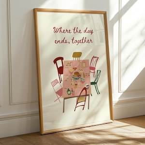 Puede incluir: Una impresión artística enmarcada que presenta una escena de mesa de comedor con un mantel rosa, rodeada de sillas coloridas. El texto "Where the day ends, together" está escrito en escritura roja encima de la mesa. El marco es de color marrón claro.