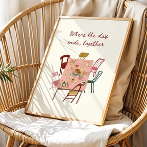 Puede incluir: Una impresi&oacute;n art&iacute;stica enmarcada que presenta una escena de mesa de comedor con sillas, platos y comida. El texto "Where the day ends, together" est&aacute; escrito en borgo&ntilde;a. La impresi&oacute;n se muestra en una silla de mimbre.
