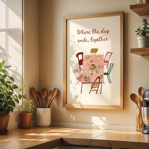 Puede incluir: Una impresi&oacute;n enmarcada con el texto "Where the day ends, together" sobre una colorida ilustraci&oacute;n de una mesa de comedor preparada para una comida. La impresi&oacute;n est&aacute; en un marco de madera clara. La imagen est&aacute; en un entorno de cocina con plantas y utensilios de madera.