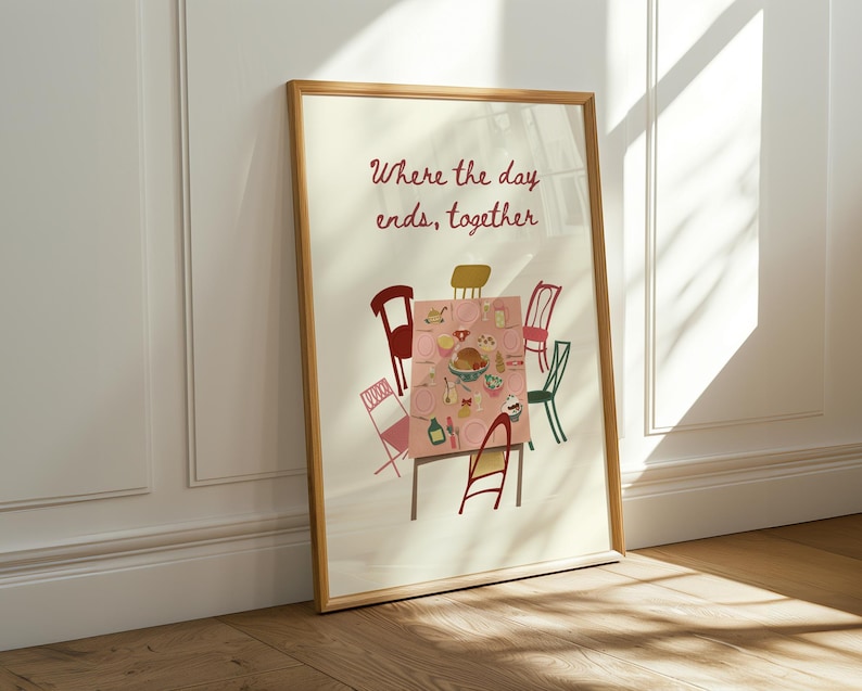 Puede incluir: Una impresi&oacute;n art&iacute;stica enmarcada que presenta una escena de mesa de comedor con un mantel rosa, rodeada de sillas coloridas. El texto "Where the day ends, together" est&aacute; escrito en escritura roja encima de la mesa. El marco es de color marr&oacute;n claro.