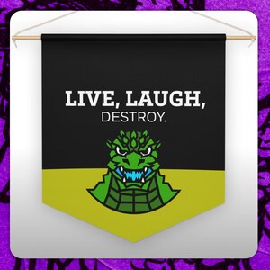 Puede incluir: Bandera negra con el texto "LIVE, LAUGH, DESTROY." con un gráfico de monstruo verde con dientes azules. La bandera tiene una parte inferior amarilla y está suspendida de una varilla de madera.