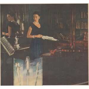 May include: An artistic image of a woman in a dark dress holding a paper, with a violin and a bookshelf in the background. The image also includes a close-up of silverware.
