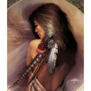 May include: A decorative plate featuring a woman with long brown hair, adorned with feathers. The woman is facing away, with a serene expression. The feathers are in shades of red, brown, and white. The plate has a gold rim.