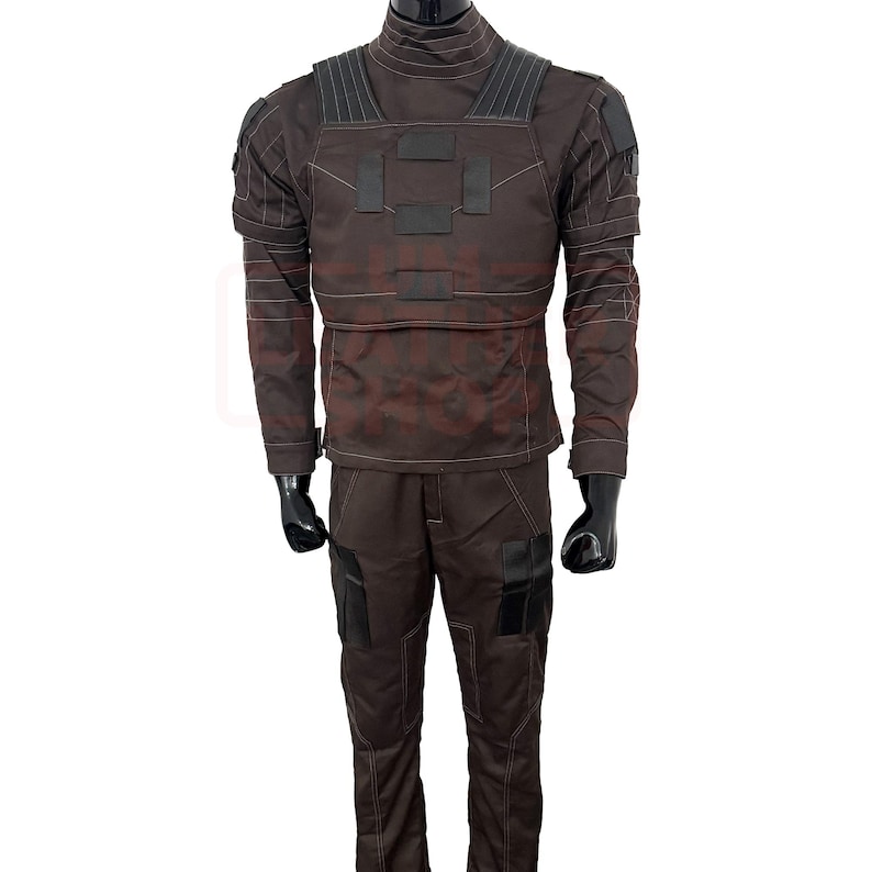 May include: A brown tactical jumpsuit with a high collar, featuring reinforced panels on the chest and shoulders. The outfit includes matching pants with pockets and black gloves. The overall design suggests a military or tactical theme.