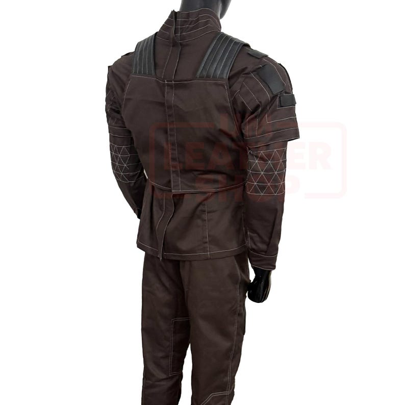 May include: Brown costume with white stitching and black accents. The outfit includes a jacket with a high collar and shoulder pads, and matching pants. The sleeves have a geometric pattern. The costume is displayed on a mannequin.