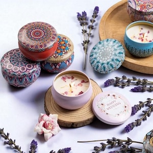 Può includere: Una collezione di candele decorative in piccoli contenitori rotondi con intricati disegni mandala. Le candele sono in vari colori, tra cui rosso, blu e rosa, e alcune sono accese. Rami di lavanda e un vassoio di legno completano l'estetica.