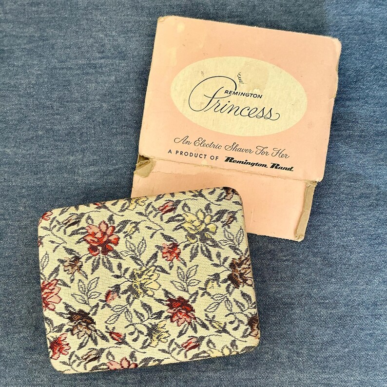 Pu&ograve; includere: Rasoio elettrico Remington Princess vintage nella sua scatola rosa originale. La scatola recita "An Electric Shaver For Her". La custodia del rasoio ha un motivo floreale con fiori rossi, rosa e gialli.