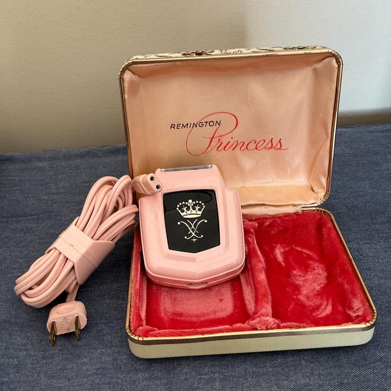Pu&ograve; includere: Un rasoio elettrico Remington Princess rosa vintage con un emblema nero con una corona e un design stilizzato. Il rasoio &egrave; nella sua custodia originale con interno rosa e fodera in velluto rosso. Un cavo rosa &egrave; arrotolato accanto alla custodia.