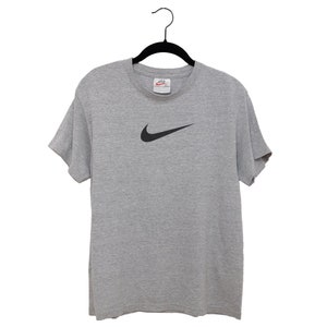 May include: A gray t-shirt with a black Nike swoosh logo.